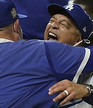 Winning manager Dave Roberts, left, hugs pitcher Julio Urias.