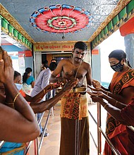 Hindu devotees receive offerings from a priest after a special prayer was held in celebration of Sen. Harris at a temple in Thulasendrapuram.