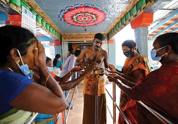 Hindu devotees receive offerings from a priest after a special prayer was held in celebration of Sen. Harris at a temple in Thulasendrapuram.