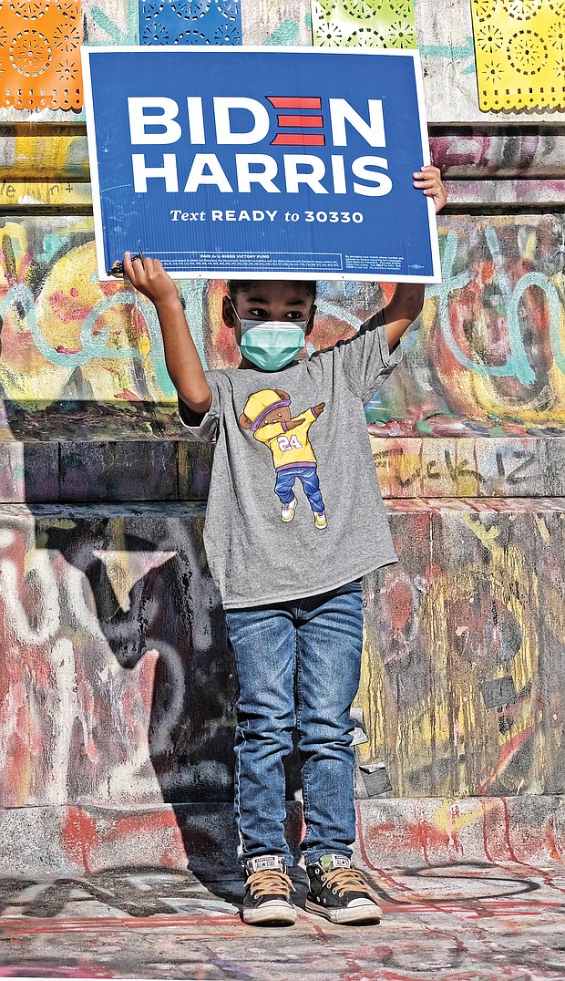 Aiden Porter holds up a biden-Harris campaign sign Saturday in celebration of the Democrats’ victory in the presidential election. The 4-year-old stood at the base of the Lee statue on Monument Avenue, where he was celebrating with his mother, Jasmine Howell.