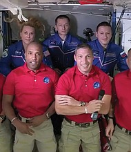 In this frame grab from NASA TV, the SpaceX Dragon crew, from front left to right, Shannon Walker, Victor Glover, Mike Hopkins and Soichi Noguchi stand with the International Space Station crew, Kate Rubins, back row from left, Expedition 64 commander Sergey Ryzhikov and Sergey Kud-Sverchkov during a welcome ceremony, early Tuesday. The Dragon arrived and docked at the ISS late Monday.