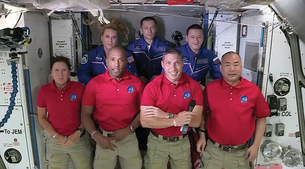 In this frame grab from NASA TV, the SpaceX Dragon crew, from front left to right, Shannon Walker, Victor Glover, Mike Hopkins and Soichi Noguchi stand with the International Space Station crew, Kate Rubins, back row from left, Expedition 64 commander Sergey Ryzhikov and Sergey Kud-Sverchkov during a welcome ceremony, early Tuesday. The Dragon arrived and docked at the ISS late Monday.