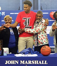 John Marshall High School basketball standout Roosevelt Wheeler, who at 6-foot-10 is one of the most recruited high school players in the nation, announces his decision to attend the University of Louisville on Monday in the North Side school’s gym. Joining him for the announcement celebration are, from left, his sister, Courtney Ingram of Atlanta; his mom, Deborah Davis of Richmond; his father, Roosevelt Wheeler Sr. of Atlanta; and his brother, C.J. Smith of Atlanta.
