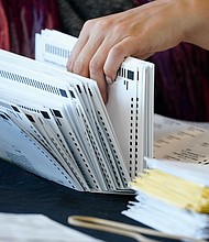 An election worker handles ballots as vote counting in the general election continues at State Farm Arena on November 5, 2020, in Atlanta.
Credit:	Brynn Anderson/AP