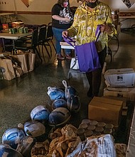 Thanksgiving is a time of gratitude and sharing the bounty of blessings with others. Richmond City Councilwoman Ellen F. Robertson, above, helps volunteers pack Thanksgiving baskets and bags
for area veterans, seniors and families at an event last Saturday she led at the Military Retirees Club in North Side.