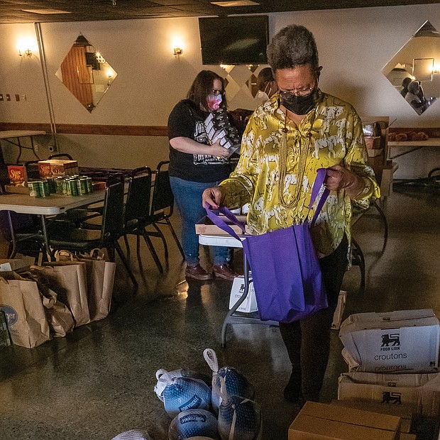 Thanksgiving is a time of gratitude and sharing the bounty of blessings with others. Richmond City Councilwoman Ellen F. Robertson, above, helps volunteers pack Thanksgiving baskets and bags
for area veterans, seniors and families at an event last Saturday she led at the Military Retirees Club in North Side.