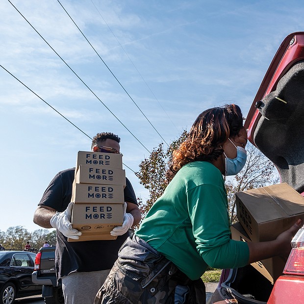 Volunteers Whitney Edmonds and Taikein Cooper help load food donated by FeedMore into a waiting car.