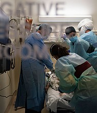 In this November 19, 2020, file photo, EMT Giselle Dorgalli, second from right, looks at a monitor while performing chest compression on a patient who tested positive for coronavirus in the emergency room at Providence Holy Cross Medical Center in the Mission Hills section of Los Angeles.
Credit: Jae C. Hong/AP