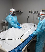Medical staff members stand by a body bag that contains a deceased COVID-19 patient's body in the COVID-19 intensive care unit at the United Memorial Medical Center on November 25, 2020 in Houston, Texas.
Credit:	Go Nakamura/Getty Images
