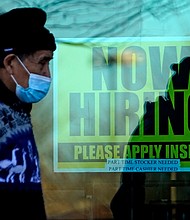 A shopper wears a face mask and he walks past a store displaying a hiring sign in Wheeling, IL.
	Nam Y. Huh/AP