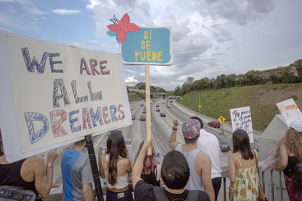 People hold signs over the 110 freeway as thousands of immigrants and supporters join the Defend DACA March to oppose the President Trump order to end DACA on Sept. 10, 2017 in Los Angeles.
Credit:	David McNew/Getty Images North America/Getty Images