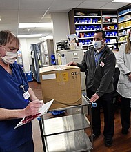 Vail Health Hospital pharmacy technician Rob Brown, left, signs the necessary paperwork to take possession of mock Covid-19 vaccines from courier driver Leo Gomez, center, as pharmacist Jessica Peterson watches over the process in the pharmacy on Dec. 8 in Vail, Colorado.
Credit:	Helen H. Richardson/MediaNews Group/The Denver Post/Getty Images
