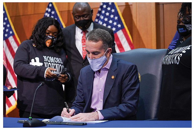 Bianca Austin, aunt of 26-year-old breonna Taylor who was killed by Louisville, Ky., police inside her apartment in March, watches as Gov. Ralph S. Northam signs a bill Monday banning no-knock warrants in Virginia. With her is the Taylor family’s lawyer, benjamin Crump. She also was accompanied at the bill signing by another one of Ms. Taylor’s aunts, Tahasha Holloway.