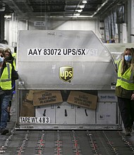 UPS employees move one of two shipping containers containing the first shipments of the Pfizer and BioNTech COVID-19 vaccine inside a sorting facility at UPS Worldport on December 13, 2020 in Louisville, Kentucky.
Credit:	Michael Clevenger/Pool/Getty Images
