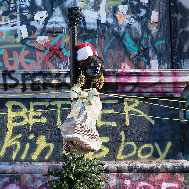 Call it protest art Christmas-style. This new artwork now stands at the base the Robert E. Lee statue on Monument Avenue. The Black figure tops a fir tree, a traditional Christmas symbol, and adds a holiday dimension to the protest slogans and colorful artwork that have transformed the pedestal that holds the Confederate statue that the state is still battling in court to take down. The pedestal, which gained its new look during the late spring and summer protests over racial injustice and police brutality, has become a significant attraction for residents and visitors. The pedestal’s changed appearance also has garnered national attention, with the New York Times naming it No. 1 on its list of protest art and National Geographic featuring it on the cover of its special issue, “2020: The year in Pictures.”