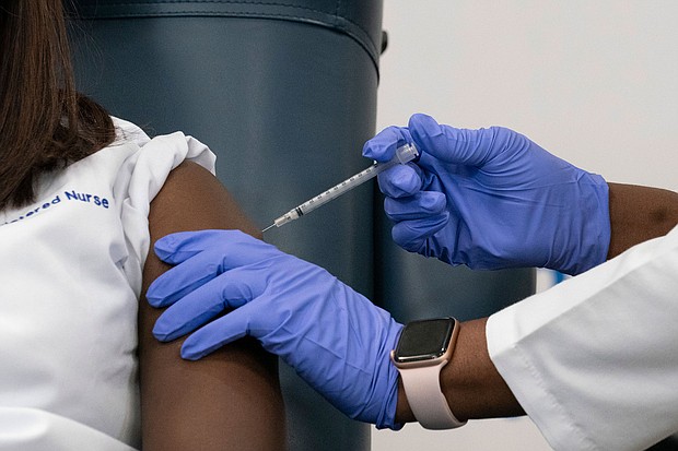 Sandra Lindsay, left, a nurse at Long Island Jewish Medical Center, is inoculated with the COVID-19 vaccine by Dr. Michelle Chester, December 14, 2020  in the Queens borough of New York City.
Credit:	Mark Lennihan/Pool/Getty Images