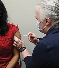 Tracey Avery-Geter, a nurse practitioner supervisor, gets a dose of the new Moderna vaccine Wednesday morning from Sara Noble, a clinical nurse manager, at the Richmond Health District office in Downtown.