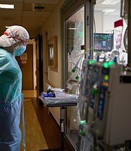 Registered Nurse Joan Pung, right, dawns her isolation gowns in the hallway inside the ICU at Providence St. Jude Medical Center Christmas Day on Friday, Dec. 25, 2020 in Fullerton, CA.
Credit:	Francine Orr/Los Angeles Times/Getty Images