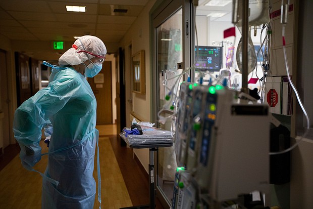 Registered Nurse Joan Pung, right, dawns her isolation gowns in the hallway inside the ICU at Providence St. Jude Medical Center Christmas Day on Friday, Dec. 25, 2020 in Fullerton, CA.
Credit:	Francine Orr/Los Angeles Times/Getty Images