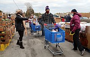 Volunteer Jeff Dean, 53, of North Chesterfield, center, maneuvers among the pallets of fresh fruit and produce where other volunteers fill his grocery cart with food. He then will load the food into one of the hundreds of cars waiting at the Chesterfield Food bank.