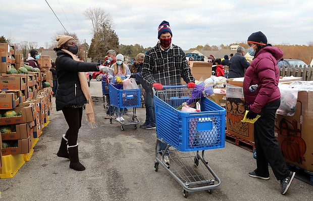 Volunteer Jeff Dean, 53, of North Chesterfield, center, maneuvers among the pallets of fresh fruit and produce where other volunteers fill his grocery cart with food. He then will load the food into one of the hundreds of cars waiting at the Chesterfield Food bank.