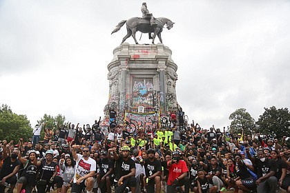 Cyclists participating in the Black Lives Matter Father’s Day Bike Ride on June 21 organized by the Urban Cycling Group and R&B singer Trey Songz of Petersburg stop at the graffiti-covered statue for a photo.