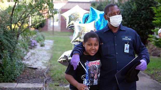 James Green, left, the custodian crew leader at Chimborazo Elementary School, receives a hug from his grandson, Mykhi Davis, 9, after being surprised Oct. 2 by Richmond Public Schools officials honoring him for 43 years of service to RPS students and families. The occasion was National Custodial Workers Day.