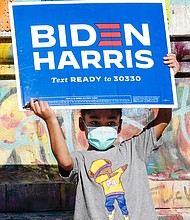 Aiden Porter holds up a Biden-Harris campaign sign Nov. 7 in celebration of the Democrats’ victory in the presidential election. The 4-year-old stood at the base of the Lee statue on Monument Avenue, where he was celebrating with his mother, Jasmine Howell.