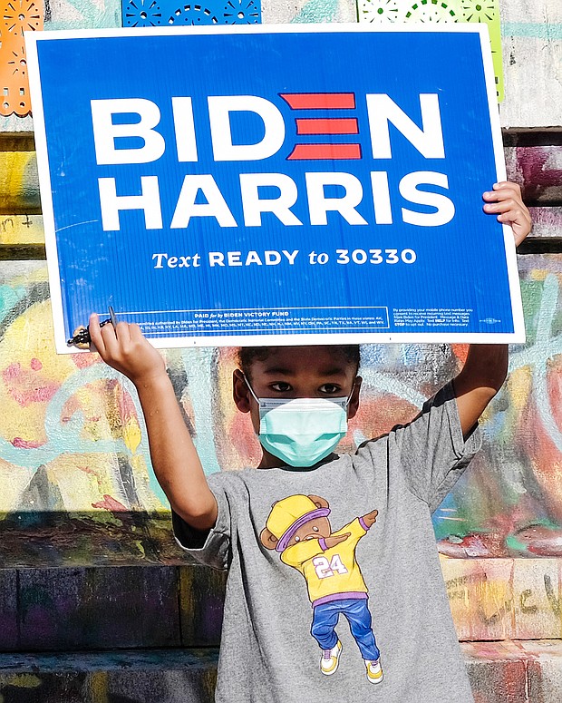 Aiden Porter holds up a Biden-Harris campaign sign Nov. 7 in celebration of the Democrats’ victory in the presidential election. The 4-year-old stood at the base of the Lee statue on Monument Avenue, where he was celebrating with his mother, Jasmine Howell.