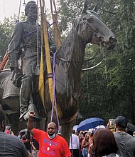 A cheering crowd watches as a crane hauls away the massive, 100-year-old statue of Confederate Gen. Thomas “Stonewall” Jackson from its pedestal at Monument Avenue and Arthur Ashe Boulevard during a downpour on July 1. Using an emergency declaration, Mayor Stoney ordered the city-owned Confederate statues to be removed as a public safety measure.