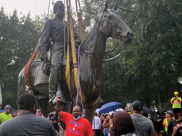 A cheering crowd watches as a crane hauls away the massive, 100-year-old statue of Confederate Gen. Thomas “Stonewall” Jackson from its pedestal at Monument Avenue and Arthur Ashe Boulevard during a downpour on July 1. Using an emergency declaration, Mayor Stoney ordered the city-owned Confederate statues to be removed as a public safety measure.