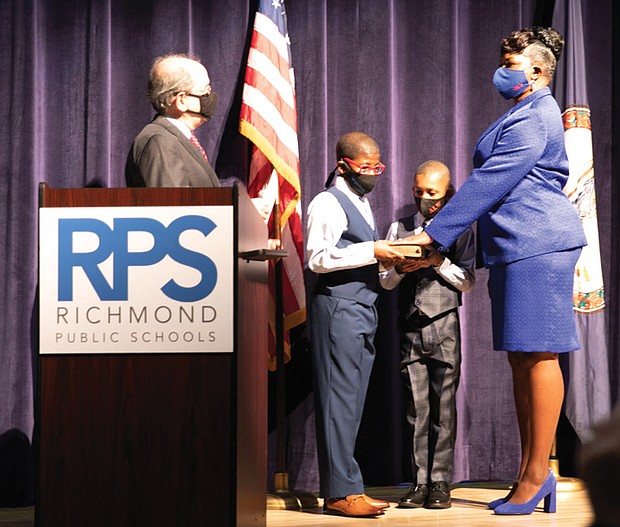 New Richmond School Board member Mariah L. White, 2nd District, is sworn in Monday by Richmond Circuit Court Clerk Edward F. Jewett with her sons, Lehman White, 12, left, and Alijah White, 9, holding the Bible. Mrs. White is among four new members on the nine-member board.