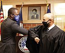 Mayor Levar M. Stoney, left, gives an elbow bump greeting to his college friend, Virginia Beach Circuit Court Judge Kevin Duffan, who administered the oath of office Monday during a small ceremony inside the new Henry L. Marsh III Elementary School in Church Hill.