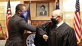 Mayor Levar M. Stoney, left, gives an elbow bump greeting to his college friend, Virginia Beach Circuit Court Judge Kevin Duffan, who administered the oath of office Monday during a small ceremony inside the new Henry L. Marsh III Elementary School in Church Hill.