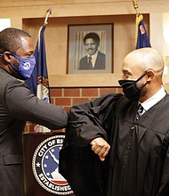 Mayor Levar M. Stoney, left, gives an elbow bump greeting to his college friend, Virginia Beach Circuit Court Judge Kevin Duffan, who administered the oath of office Monday during a small ceremony inside the new Henry L. Marsh III Elementary School in Church Hill.