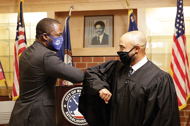 Mayor Levar M. Stoney, left, gives an elbow bump greeting to his college friend, Virginia Beach Circuit Court Judge Kevin Duffan, who administered the oath of office Monday during a small ceremony inside the new Henry L. Marsh III Elementary School in Church Hill.