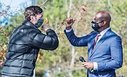 Jon Ossoff, left, and Raphael Warnock exchange elbow bumps Monday during a campaign rally in Augusta, Ga. Democrats Ossoff and Warnock won their respective racdes against incumbent Republican Sens. David Perdue and Kelly Loeffler in a runoff election Jan. 5.