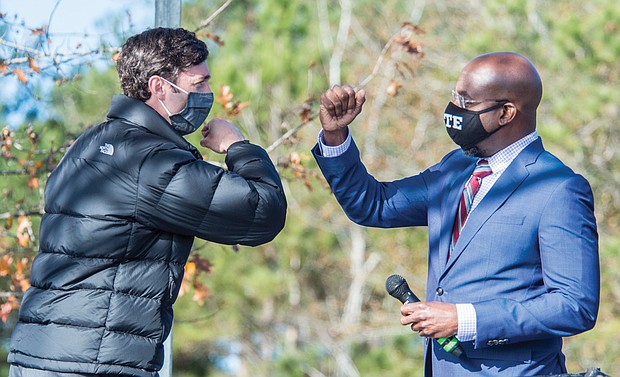 Jon Ossoff, left, and Raphael Warnock exchange elbow bumps Monday during a campaign rally in Augusta, Ga. Democrats Ossoff and Warnock won their respective racdes against incumbent Republican Sens. David Perdue and Kelly Loeffler in a runoff election Jan. 5.