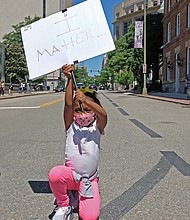 Nasiah Morris, 4, carries a sign with a powerful message during a peaceful grassroots march May 31 from Brown’s Island to the 17th Street Market in Shockoe Bottom. The youngster, kneeling at 9th and Grace streets across from the State Capitol, attended the rally with her mother, Toya Morris, and 15-year-old brother, Tye.