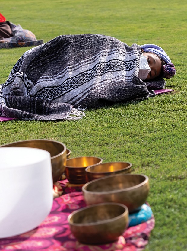 Treasure Daily, 10, is bundled up in the outfield of The Diamond listening as her mother, Shanna Latia, conducts sound therapy during Project Yoga Richmond’s Saturday Salutations on Sept. 19. The nonprofit organization has worked to make yoga affordable and accessible to Richmonders, particularly during the current high- stress times.