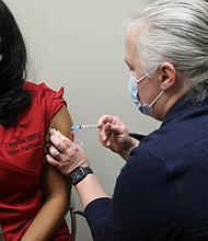 Tracey Avery-Geter, 47, of Chesterfield, a nurse practitioner supervisor, gets a dose of the new Moderna vaccine against COVID-19 on Dec. 23 from Sara Noble, a clinical nurse manager, at the Richmond Health District Office in Downtown. As a health care worker, Ms. Avery-Geter is in the top priority group designated by the state to receive the vaccine. Also in the top group: Residents and staff at long-term care facilities.