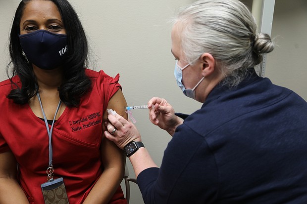 Tracey Avery-Geter, 47, of Chesterfield, a nurse practitioner supervisor, gets a dose of the new Moderna vaccine against COVID-19 on Dec. 23 from Sara Noble, a clinical nurse manager, at the Richmond Health District Office in Downtown. As a health care worker, Ms. Avery-Geter is in the top priority group designated by the state to receive the vaccine. Also in the top group: Residents and staff at long-term care facilities.