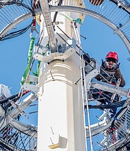 A Verizon worker doing maintenance work atop a cell tower pauses for a photo op. Location: 25th and Decatur streets in South Side.