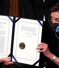 House Speaker Nancy Pelosi shows the article of impeachment against President Trump after signing it in a ceremony at the U.S. Capitol on Wednesday. It marks the first time in U.S. history that a president has been impeached twice.