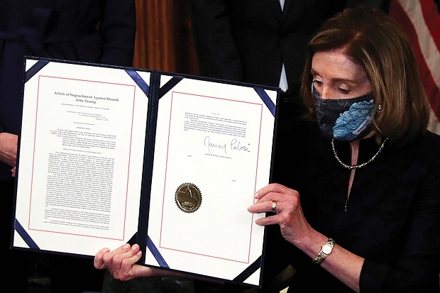 House Speaker Nancy Pelosi shows the article of impeachment against President Trump after signing it in a ceremony at the U.S. Capitol on Wednesday. It marks the first time in U.S. history that a president has been impeached twice.