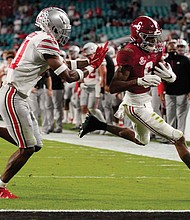 Alabama wide receiver and Heisman Trophy winner DeVonta Smith, right, runs past Ohio State University safety Josh Proctor to score a touchdown during the first half of the NCAA College Football Playoff National Championship on Monday night in Miami.