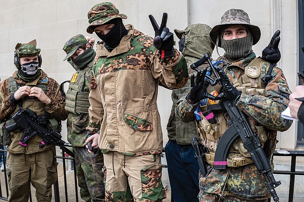 Armed gun rights advocates flash peace and love signs to media at the rally near the State Capitol. More media and police were on hand for the rally than demonstrators.