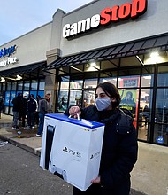 A man wearing a face masks leaves Game Stop with the new Play Station 5 gaming console on Black Friday. 
Credit:	Aimee Dilger/SOPA Images/LightRocket/Getty Images