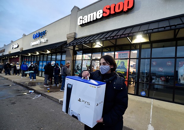 A man wearing a face masks leaves Game Stop with the new Play Station 5 gaming console on Black Friday. 
Credit:	Aimee Dilger/SOPA Images/LightRocket/Getty Images