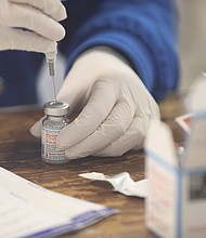 Terri Roe, a registered nurse with Henrico County Public Schools, fills syringes with the Moderna coronavirus vaccine Jan. 21 at the Old Dominion Building at the Richmond Raceway, where the Richmond and Henrico health districts are conducting mass inoculations.